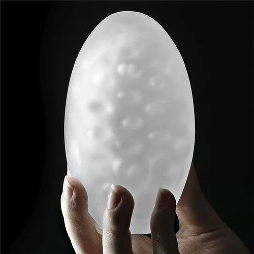 Masturbador masculino Giant Egg Stamina Nodules sostenido a contraluz para resaltar su textura y nódulos de estimulación, en un formato de huevo